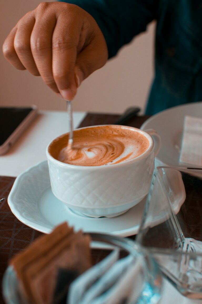 person pouring coffee on white ceramic cup