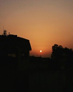 the sun is setting behind a building in the distance
