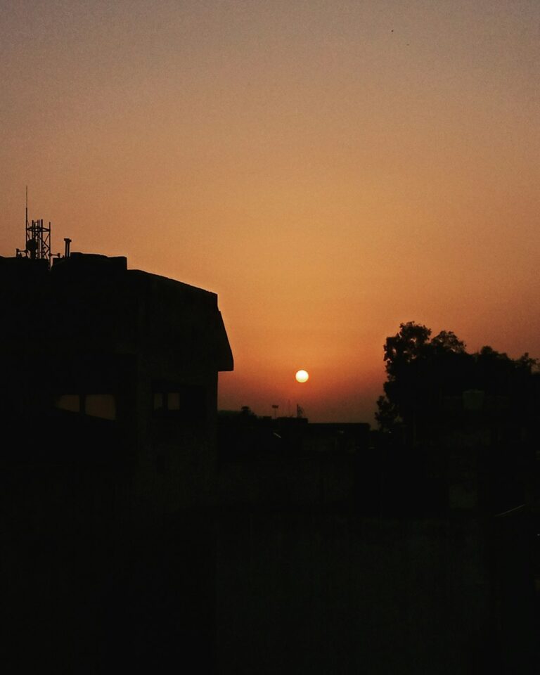 the sun is setting behind a building in the distance