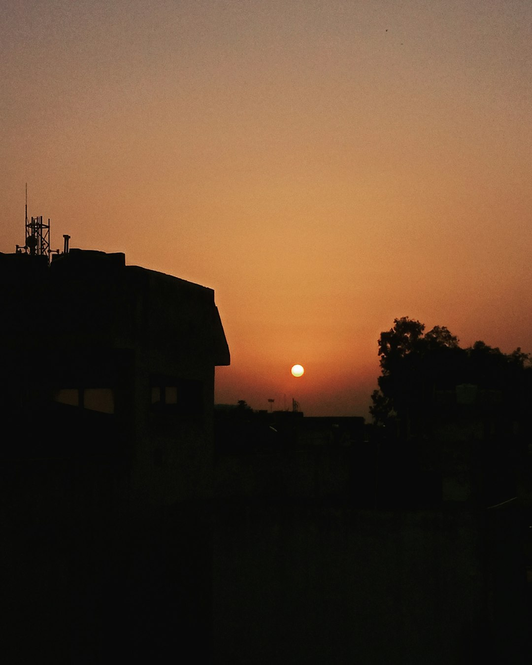 the sun is setting behind a building in the distance