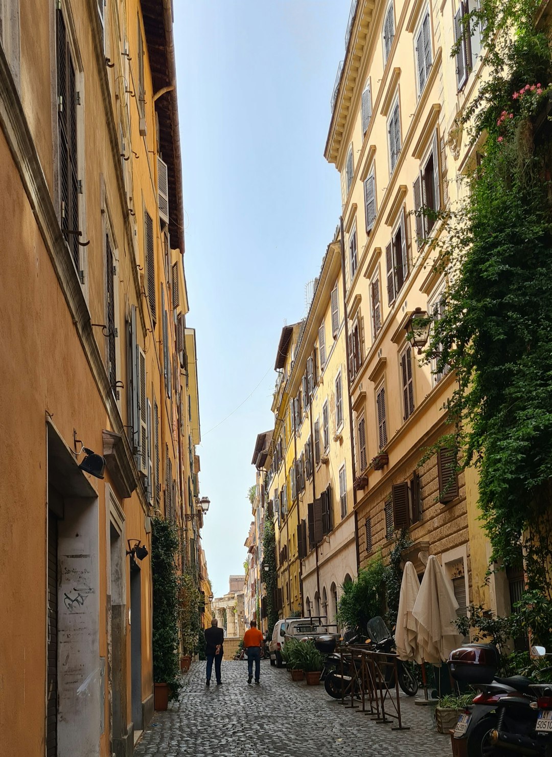 a couple of people walking down a cobblestone street