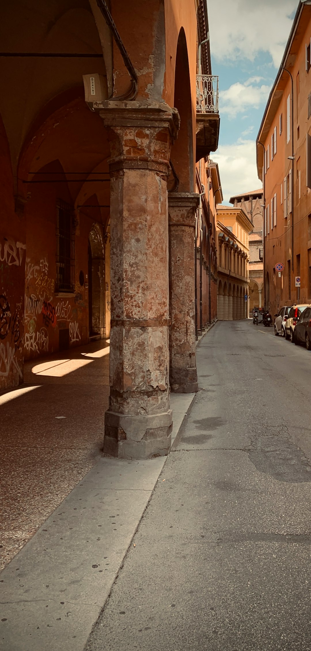 a narrow street with cars parked on both sides