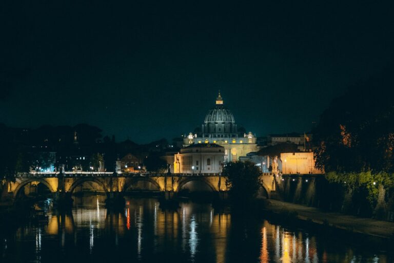 a bridge over a river leading to a building with a dome on top