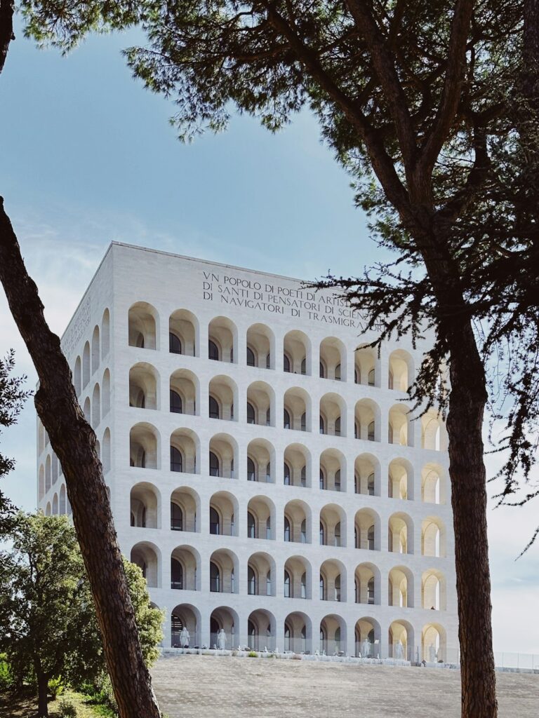 a large white building surrounded by trees on a sunny day