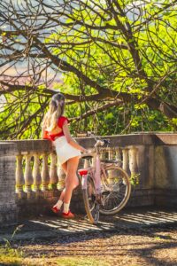 a woman standing next to a pink bike