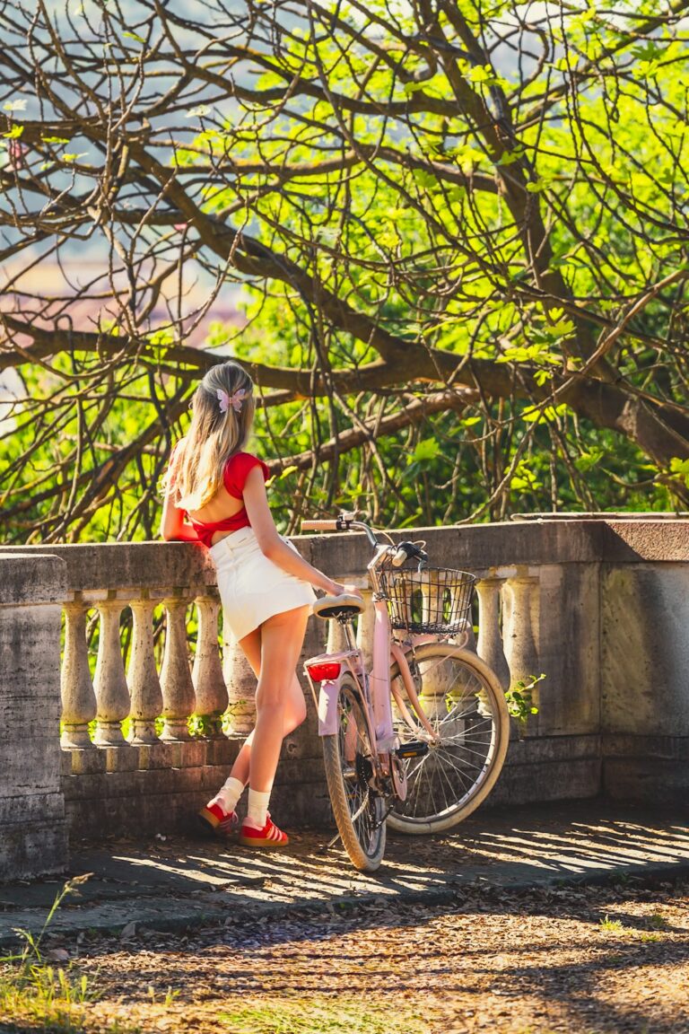 a woman standing next to a pink bike