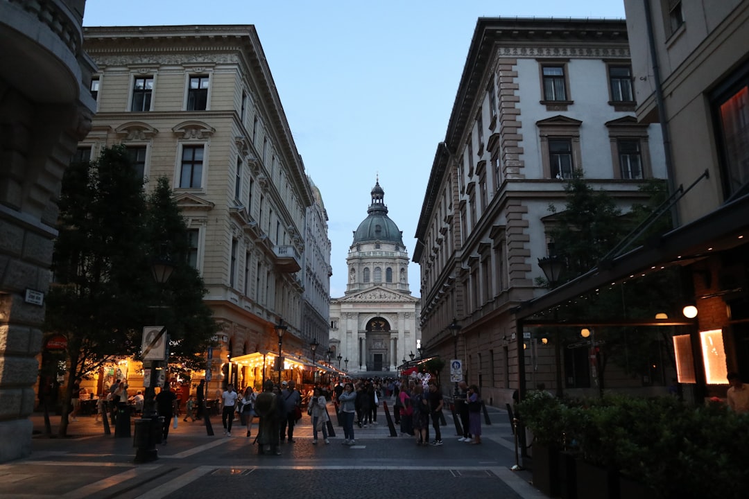 A group of people walking down a street next to tall buildings