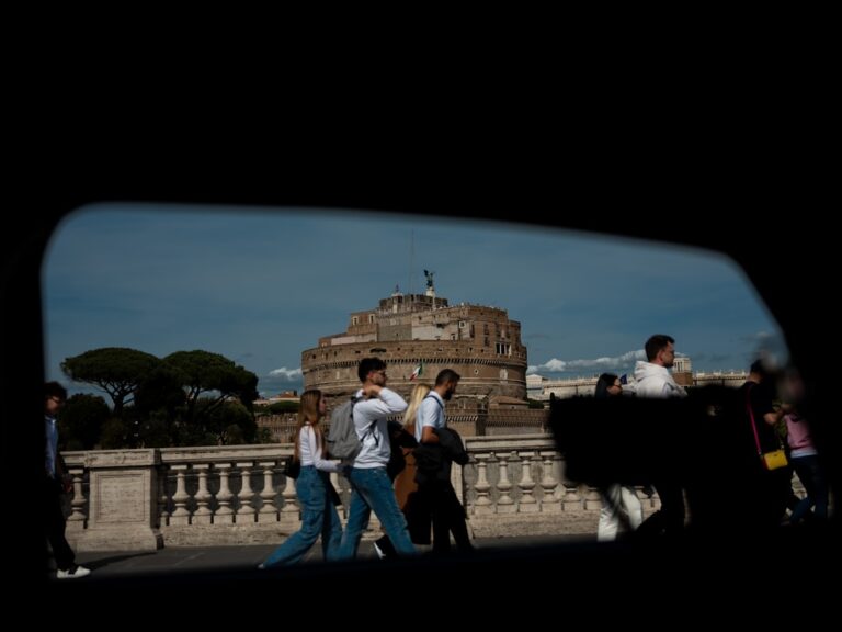 A moment in motion — Castel Sant’Angelo in Rome, viewed through the window of a passing car. Tourists drift by, unaware...