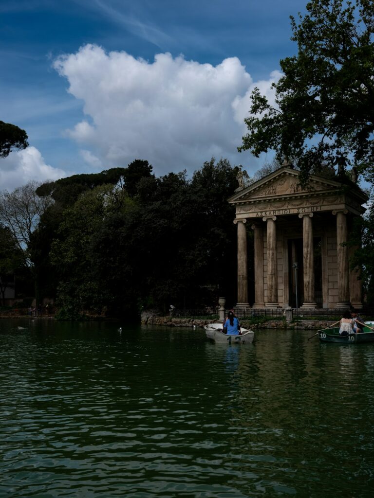 Visitors enjoy rowing boats on the tranquil waters surrounding the Temple of Asclepius in Romeβs lush Villa Borghese...