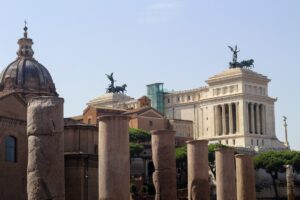 A stunning cityscape of Rome showcasing ancient Roman column ruins from the Foro Romano in the foreground, with the...