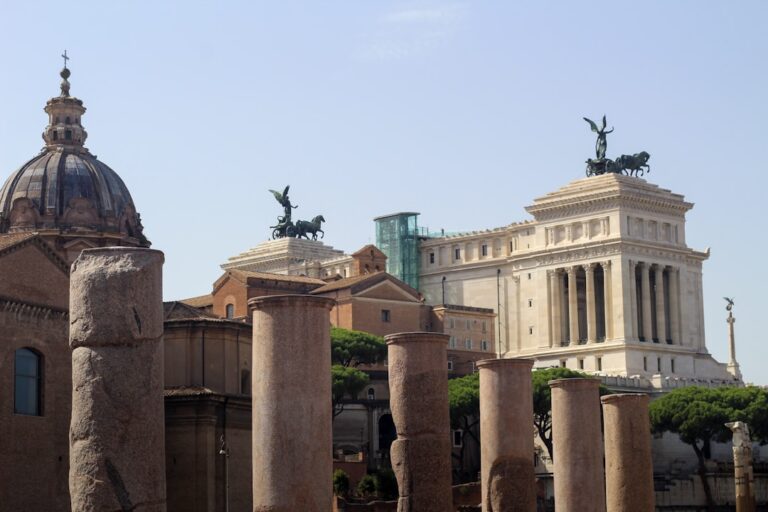 A stunning cityscape of Rome showcasing ancient Roman column ruins from the Foro Romano in the foreground, with the...