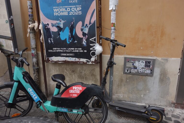 Electric scooter and bicycle parked by poster