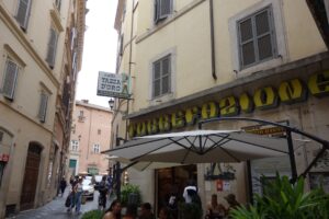 People sit outside a cafe on a narrow street.