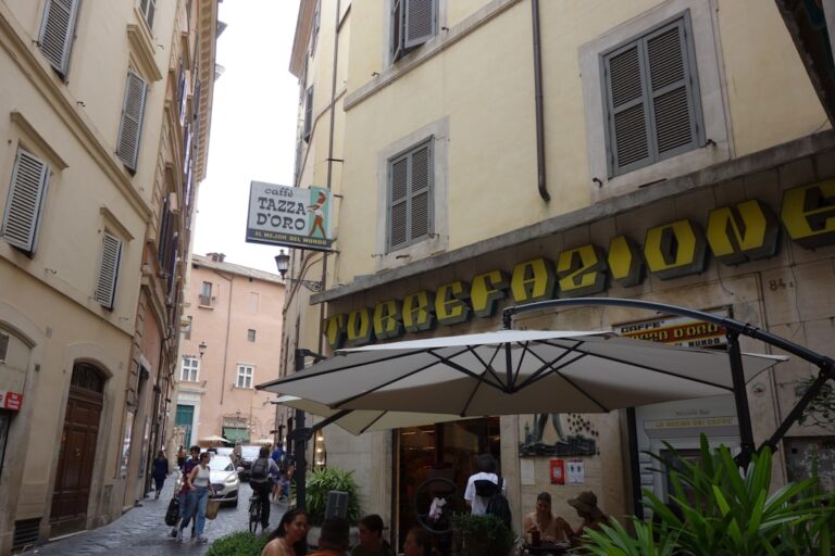 People sit outside a cafe on a narrow street.