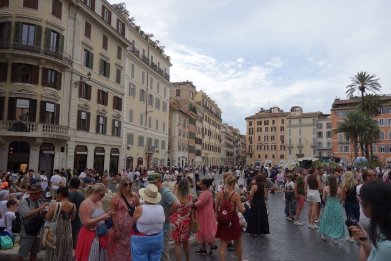 Crowded european square with historic buildings and palm trees