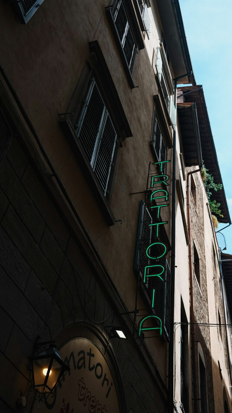 Green neon sign for trattoria on building