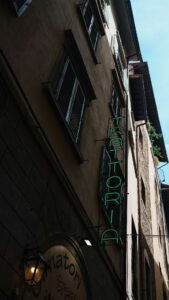Green neon sign for trattoria on building