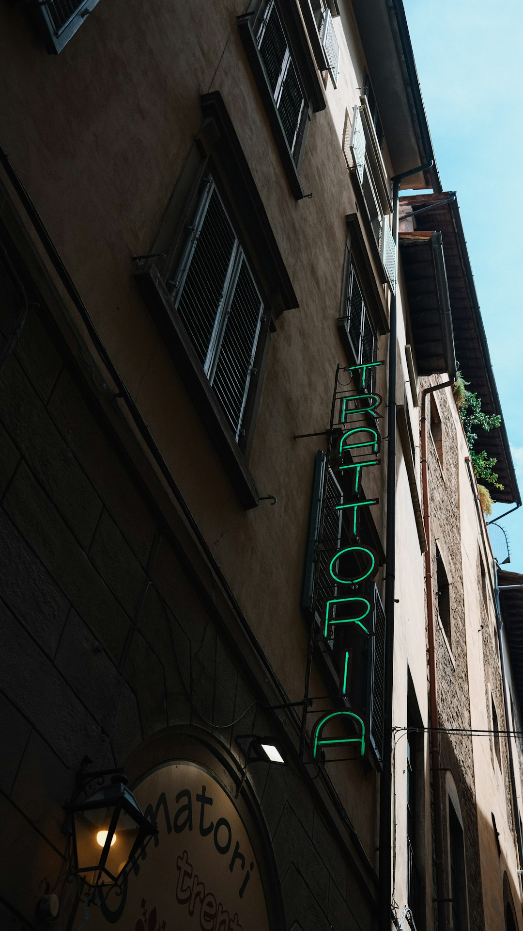 Green neon sign for trattoria on building