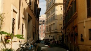Narrow street with buildings and parked scooters.