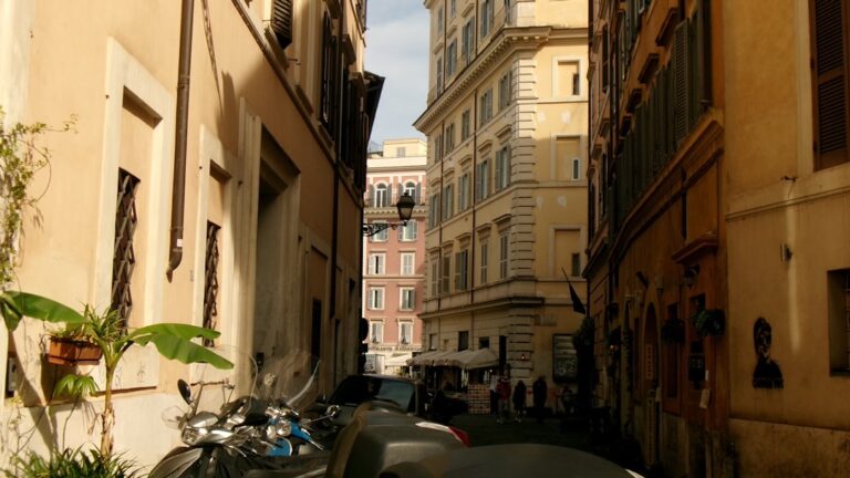 Narrow street with buildings and parked scooters.