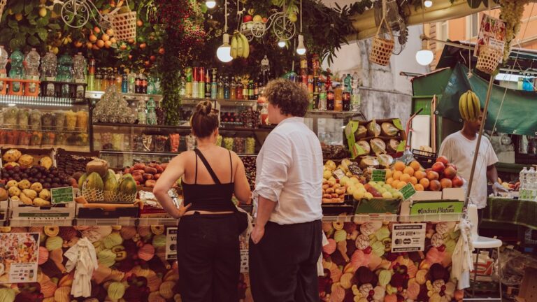 People browsing a vibrant fruit and vegetable market stall.